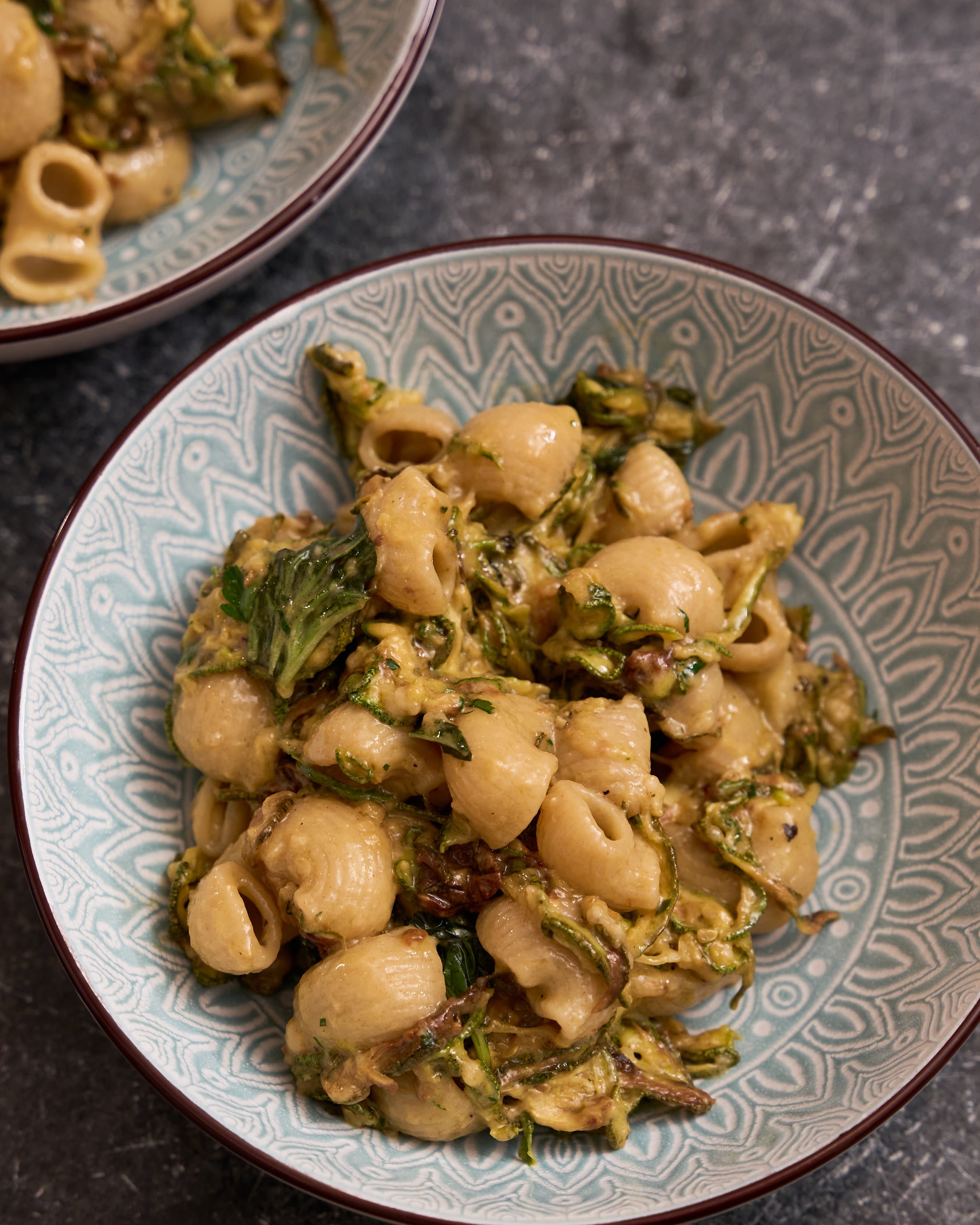 Pasta dish with greens on a patterned ceramic plate