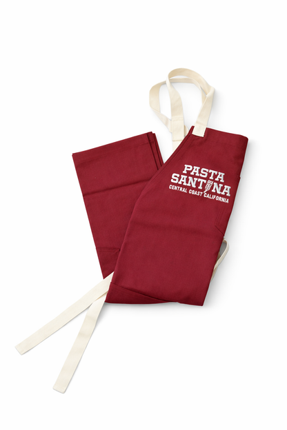 Red crossback apron, folded, with a logo on a white background
