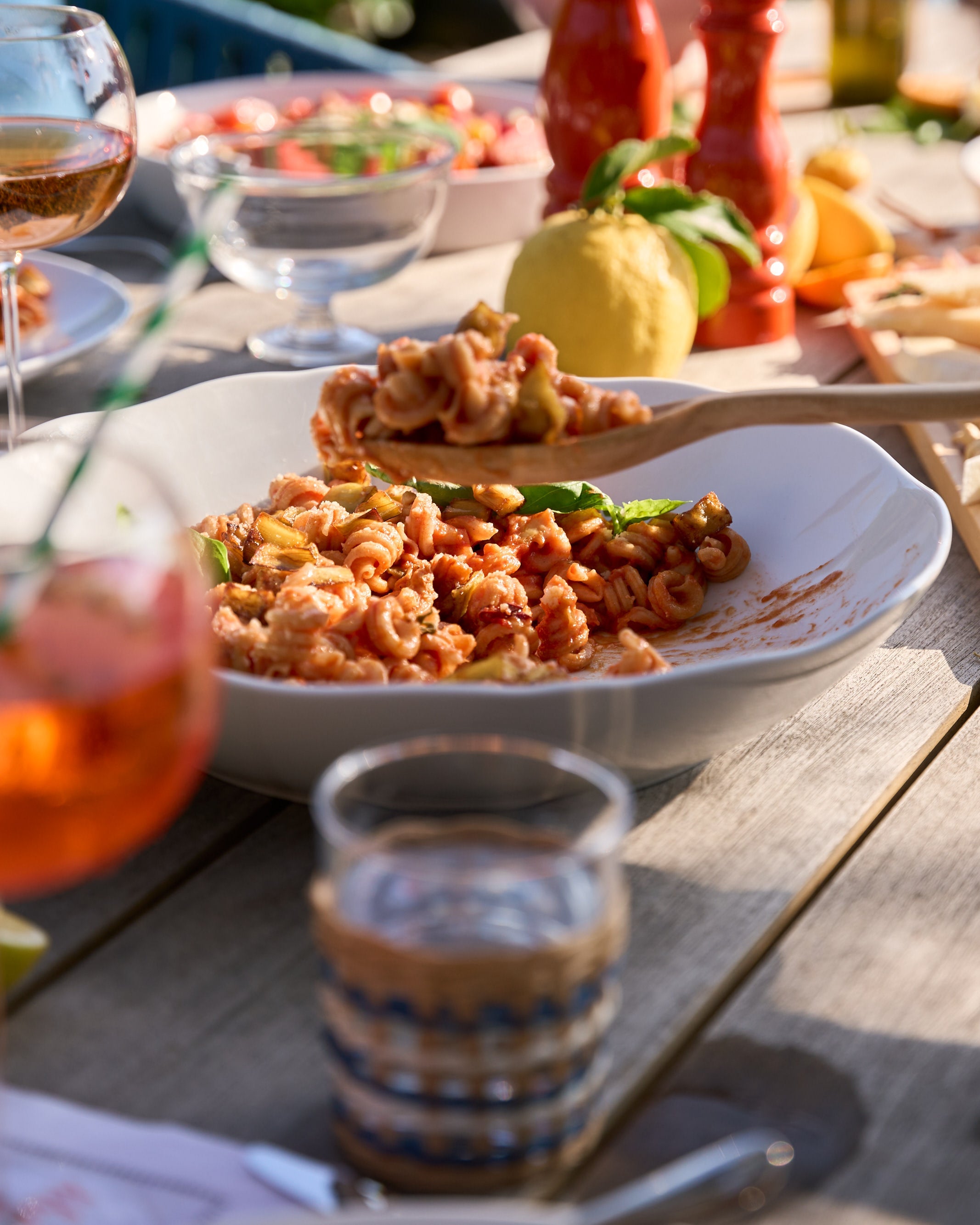 Outdoor dining scene with food and drinks on a wooden table